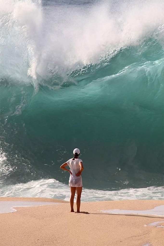 Girl standing in front of a large wave